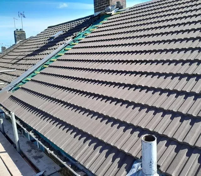 Roofer replacing broken tiles on a Surrey terraced house